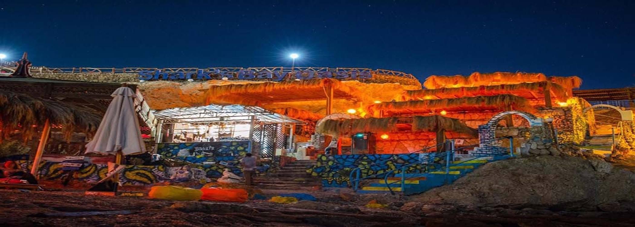 Basata Café lit up at night beneath the Shark’s Bay Oasis sign