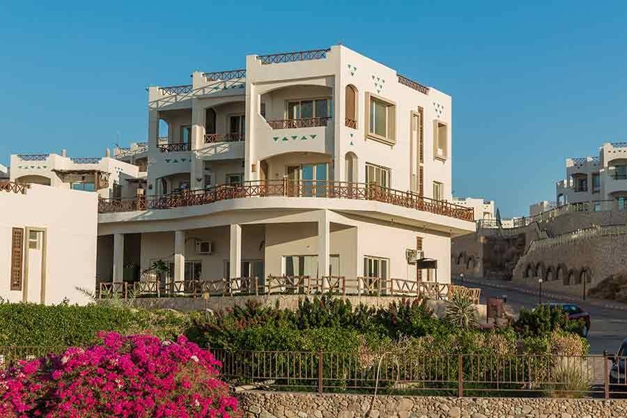 Apartments framed by bougainvillea and palms