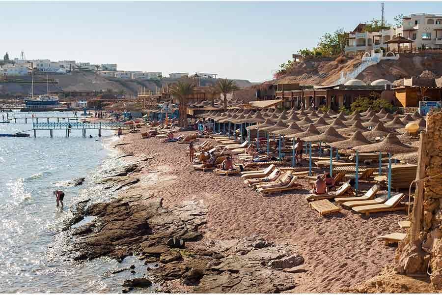 Sandy shore with umbrellas and the reef edge